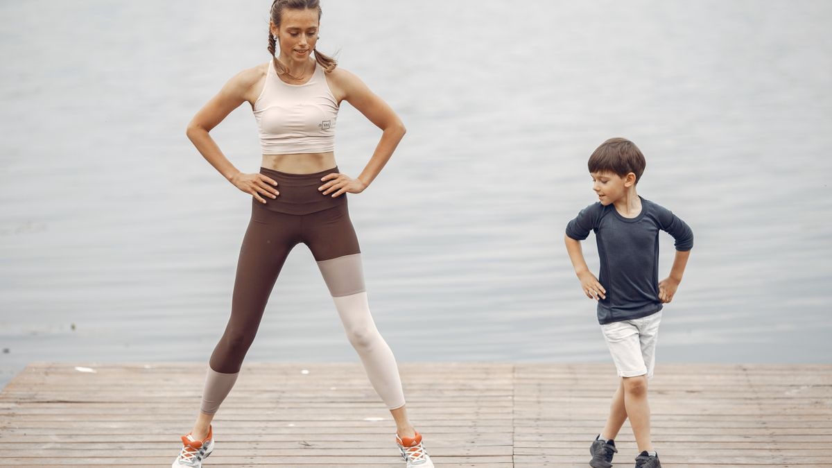 A mother and son exercising together on a wooden pier by the lake, enjoying fitness and fun.
